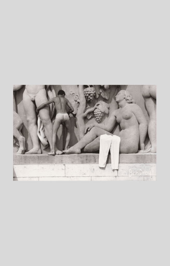 A man climbs over the fountain in the Paris Statues Jardins du Trocadéro, Paris. Trousers are draped over the leg of one of the statues.